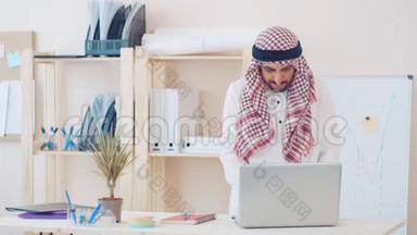 <strong>现代</strong>中东人，穿着民族服装，在<strong>办公桌</strong>前的办公室工作。 头上戴着古特拉的商人